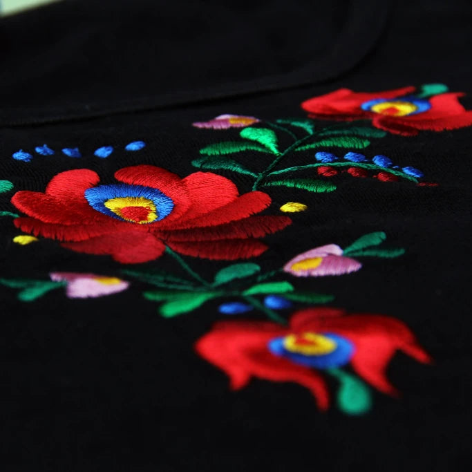 Détail de la broderie florale Matyó sur la poitrine du T shirt à fond noir et à manches longues.