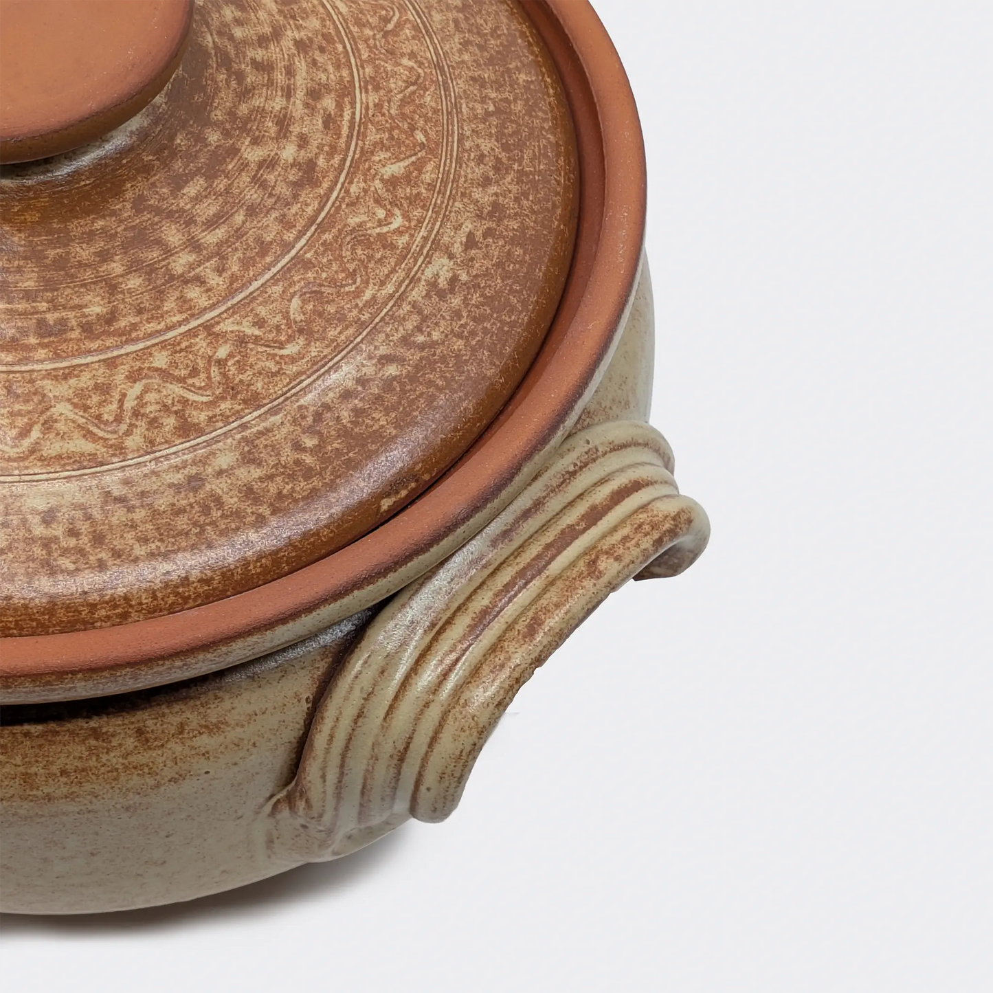 Gros plan sur la poignée latérale d’une cocotte en terre cuite artisanale 5 litres fabriquée à Corund.