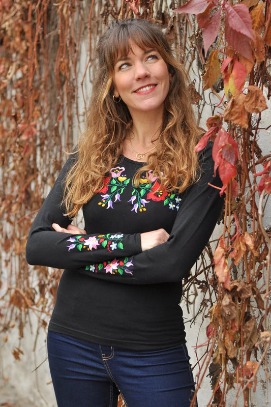 Vêtement féminin brodé Kalocsa floral, inspiration hongroise traditionnelle. Noir et à manches longues. Vue de face, un peu en biais