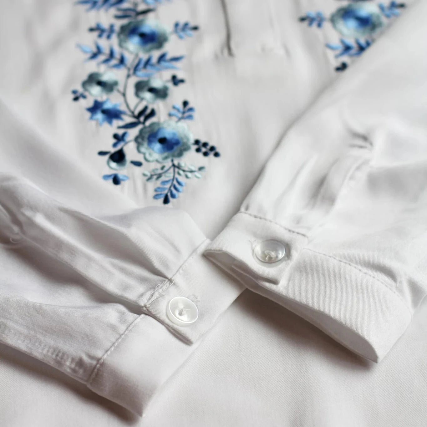 Détail des manches de la blouse. En arrière-plan on voit les fines broderies bleues et gris-argenté d'inspiration Palóc.