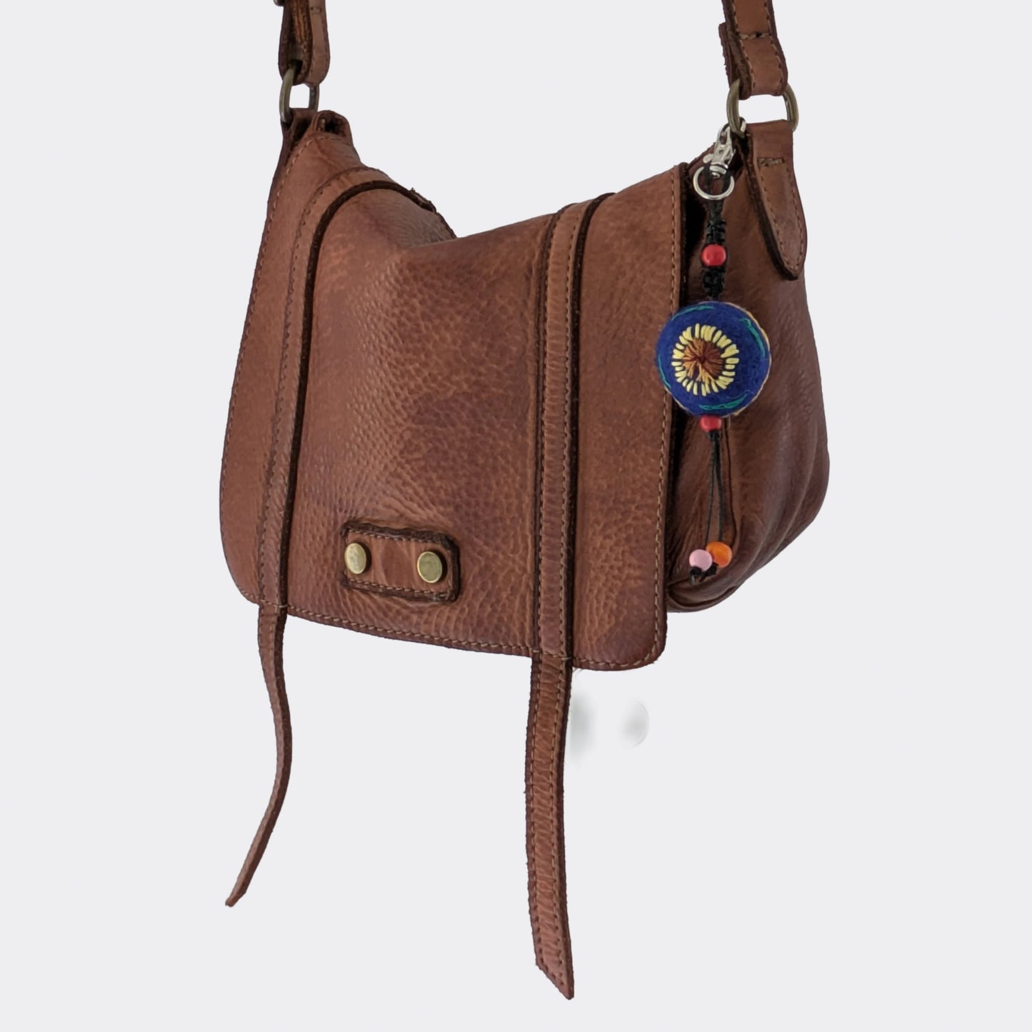 Charm de sac artisanal en feutre de laine bleu représentant un tournesol sur sac en cuir