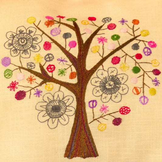 Détail des branches et fleurs d'un arbre brodé en couleurs vive sur une housse de coussin