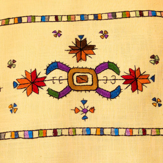 Broderie colorée du Kosovo en gros plan sur une housse de coussin en lin lavé.