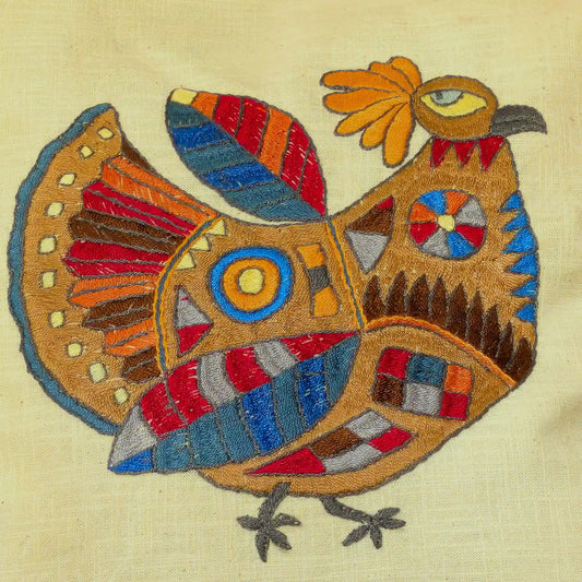 Détail de la broderie de poule stylisée en couleurs vives sur housse de coussins