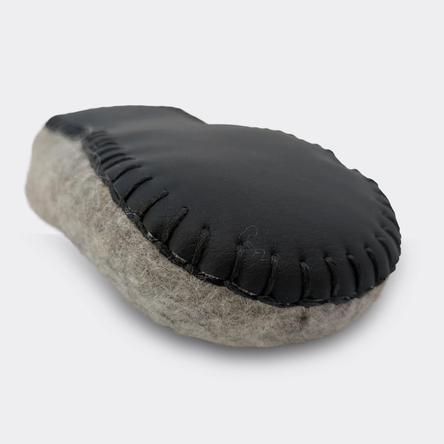 Vue de face et en gros plan de la semelle cousue sur un chausson artisanal en feutre gris en laine naturelle