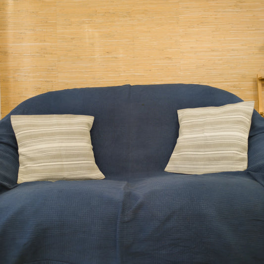 2 coussins avec housses rayées blanches et grises tissées à la main, sur un canapé