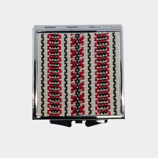 Miroir compact orné d’un motif textile rouge et noir. Le décor tissé apporte une note douce venue des Carpates. Idéal pour glisser dans un sac.