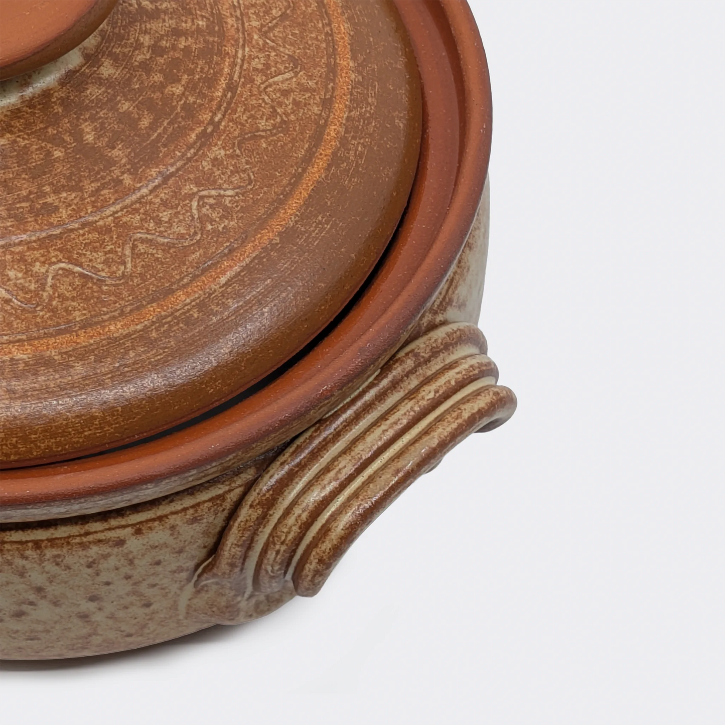 Gros plan sur la poignée latérale d’une petite cocotte en terre cuite 2 litres fabriquée à Corund.