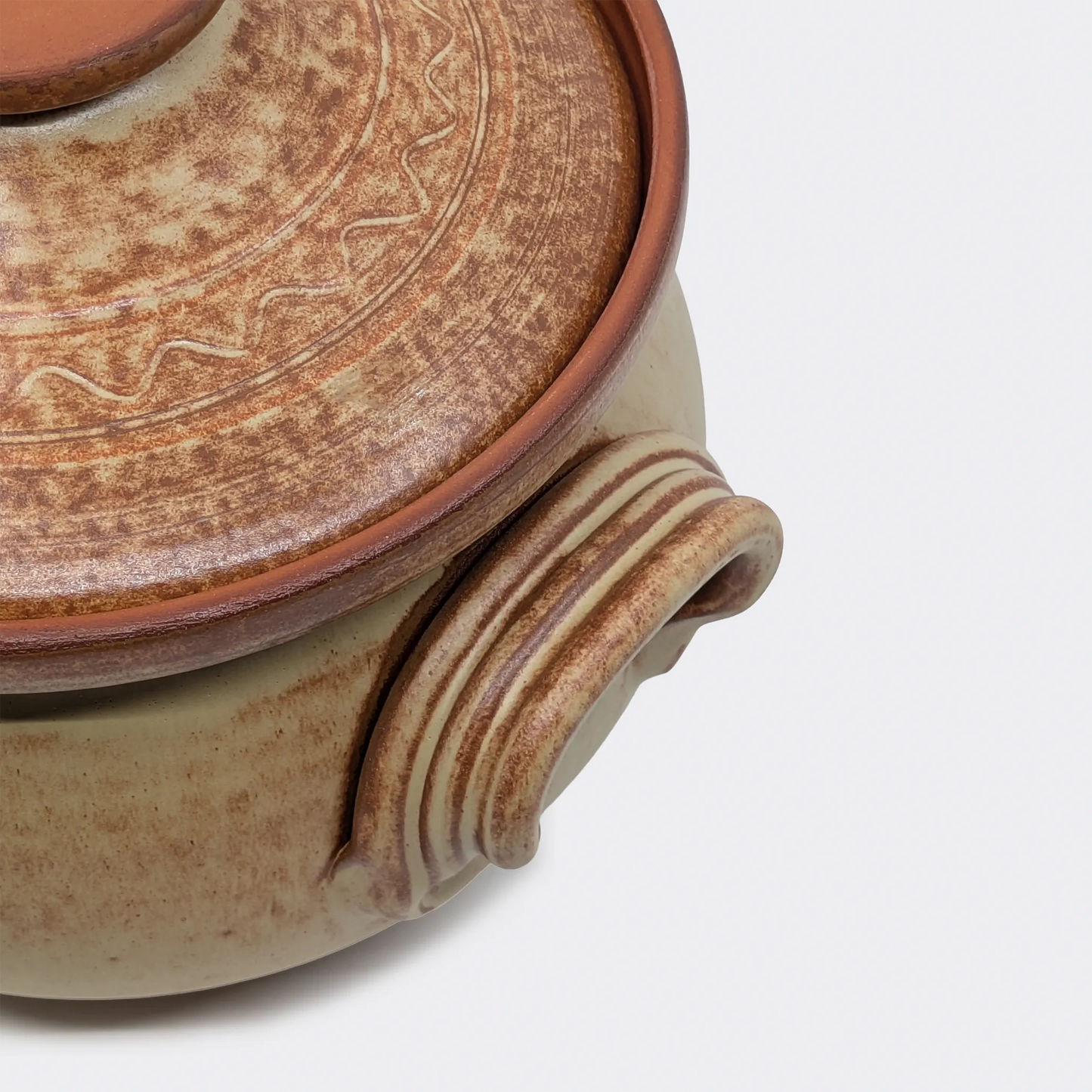 Gros plan sur la poignée latérale d’une cocotte en terre cuite 4 litres fabriquée artisanalement à Corund.