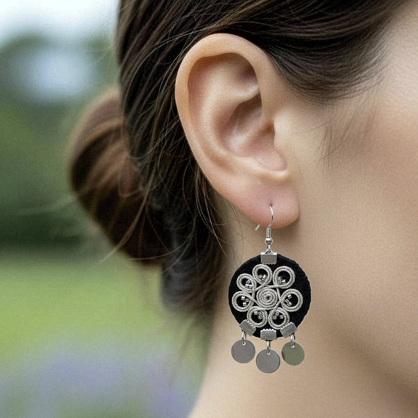 Boucle d'oreille brodée avec spirale argentée en arabesque sur fond noir