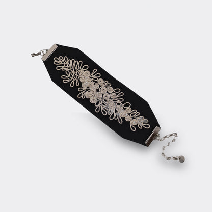 Bracelet textile noir brodé main avec un fil argenté. Les attaches métalliques en acier hypoallergénique. Modèle large.