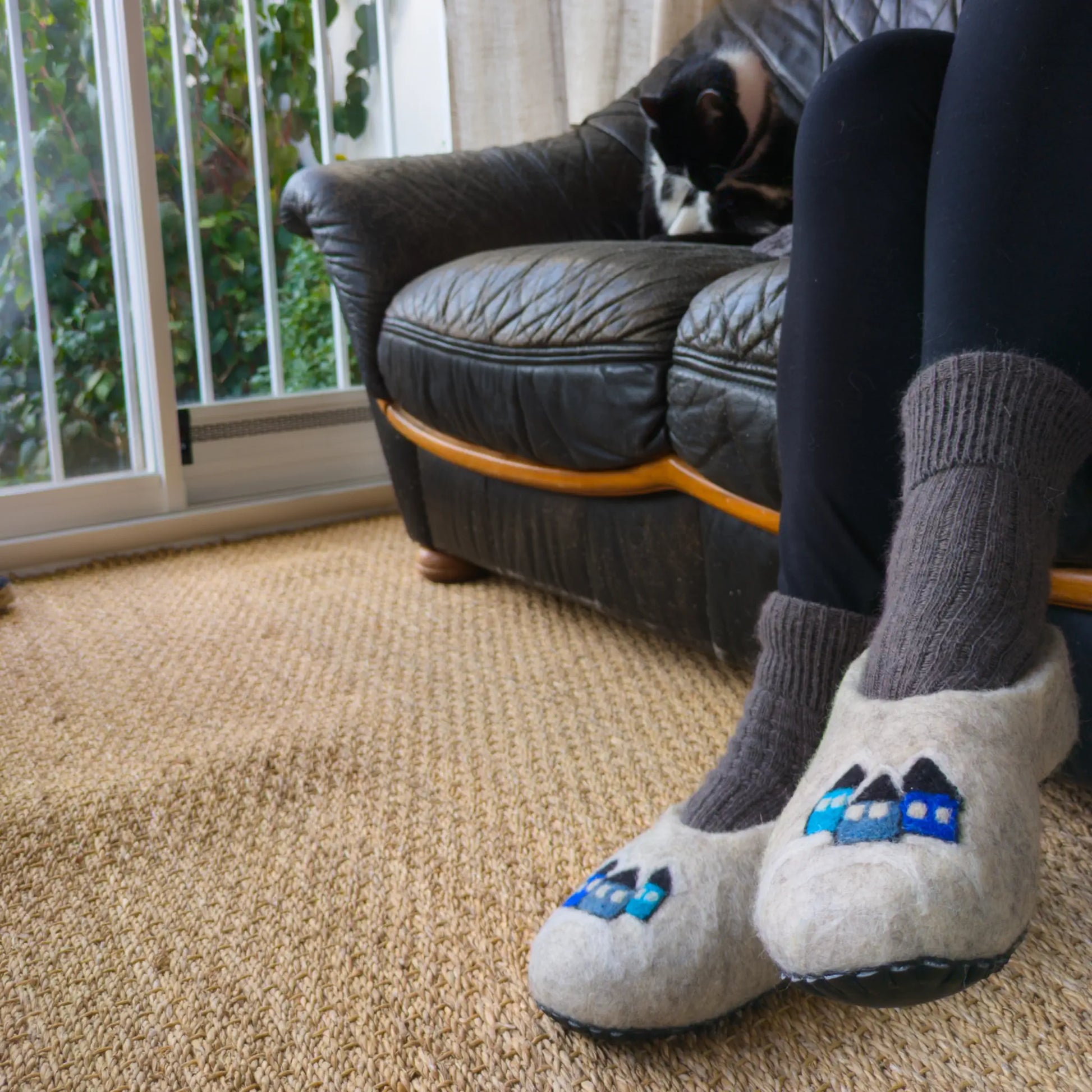 Chaussons en feutre faits main, portés, le motif est des petites maisons enneigés