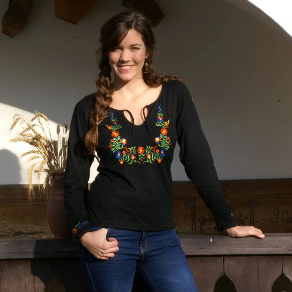 Haut noir pour femmes avec broderies colorées inspirées du style folklorique hongrois et plus exactement de la région de Béké, les motifs sont  disposés autour du col et sur les poignets. Vue de face