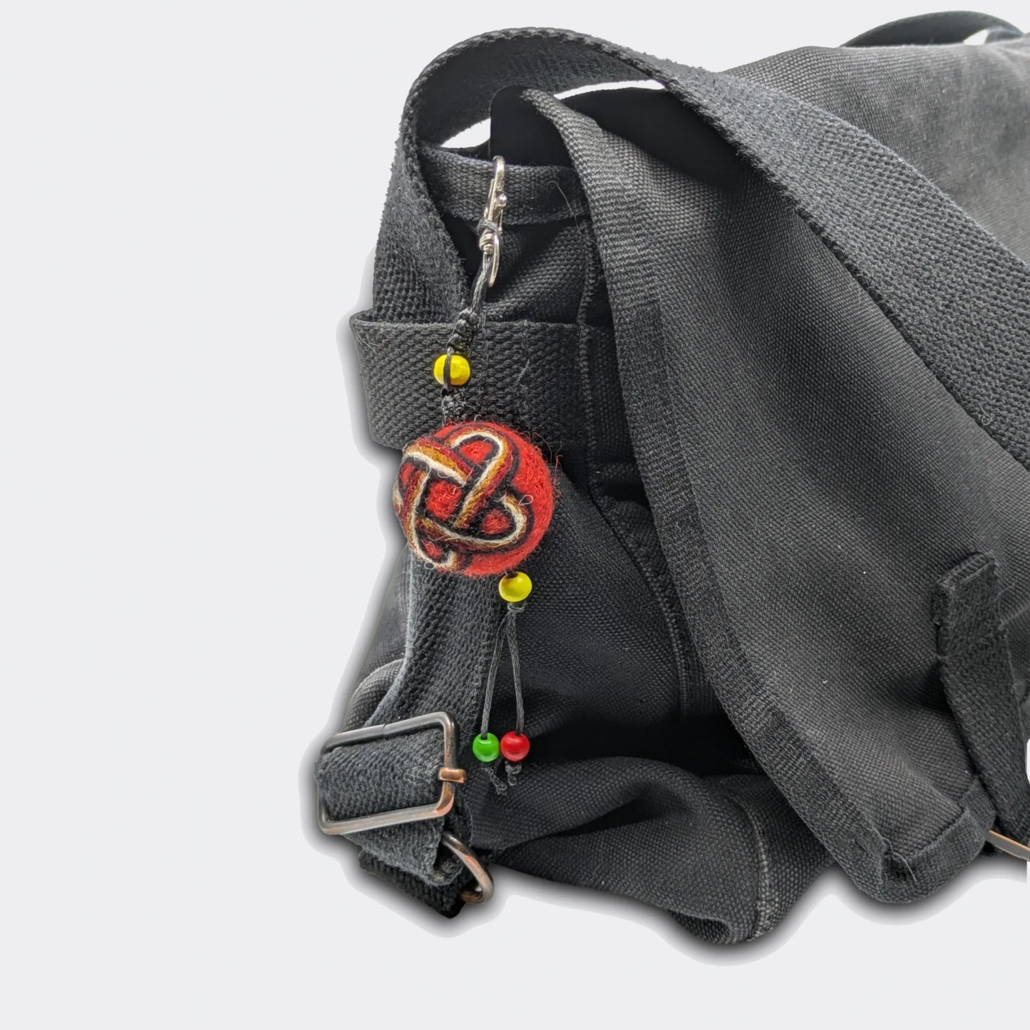 Suspension décorative Solomun constituée d'une petite boule en feutre rouge et motif nœud de Salomon sur sac à main