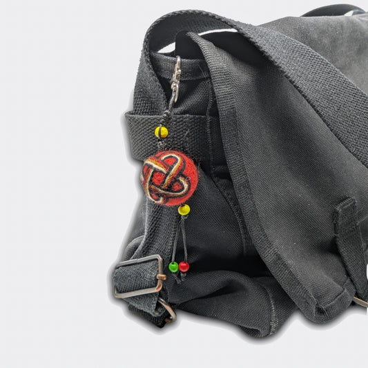 Suspension décorative Solomun constituée d'une petite boule en feutre rouge et motif nœud de Salomon sur sac à main