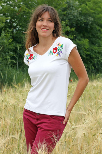 T-shirt blanc avec une broderie hongroise Kalocsa sur chaque épaule, vue légèrement de biais