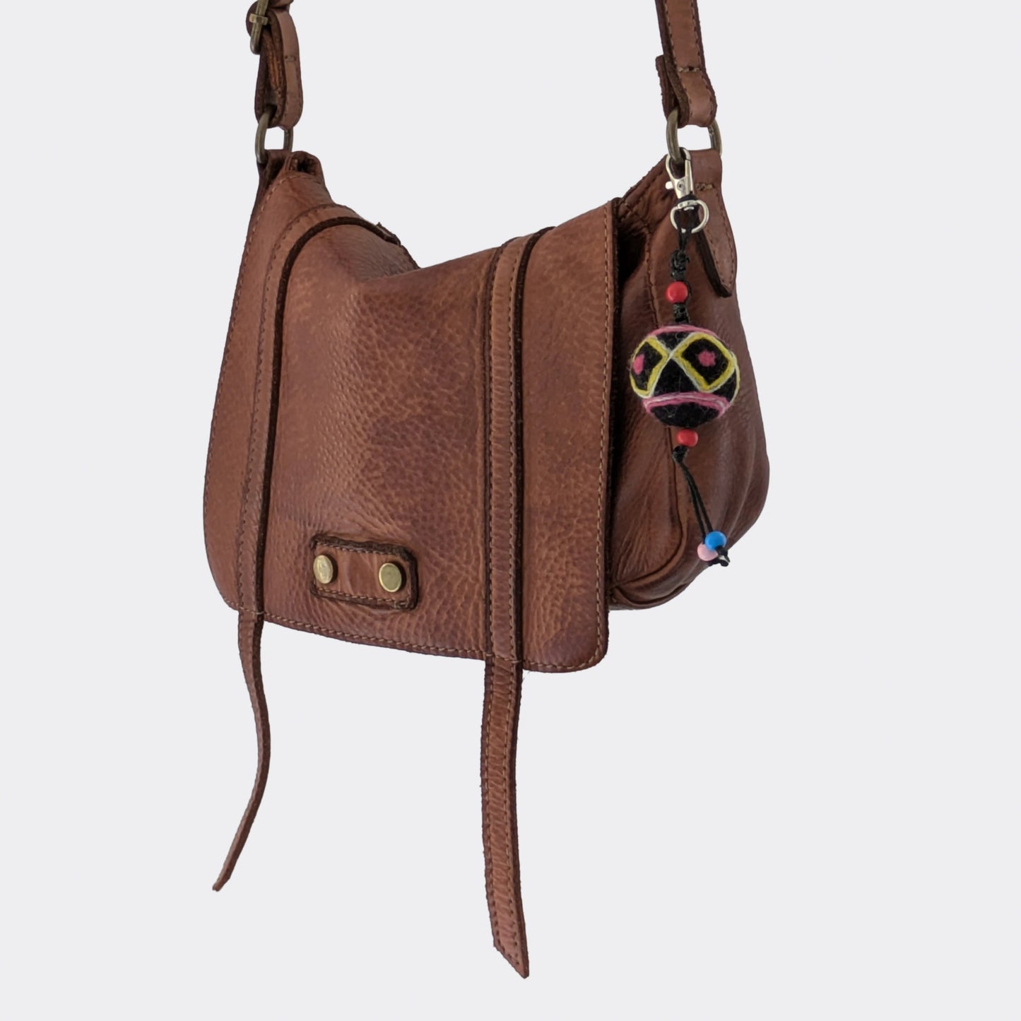Accessoire de sac avec boule en feutre travaillée à la main sur sac en cuir