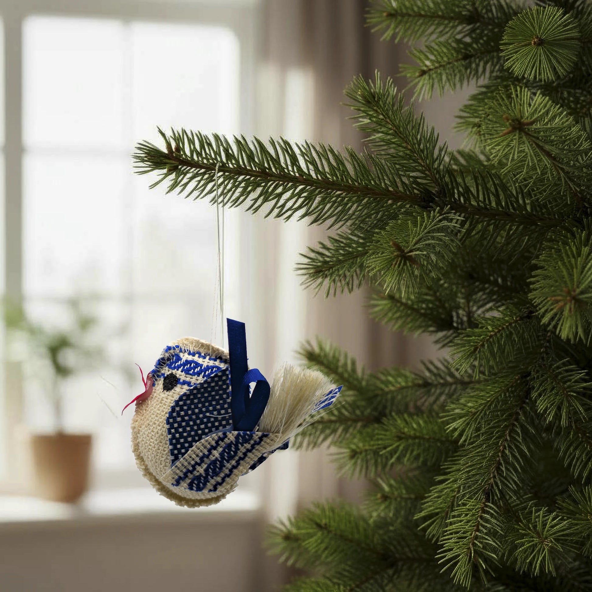 Oiseau de couleur bleue et écru suspendu à un sapin comme décoration. Artisanal, fait à la main en République Tchèque.