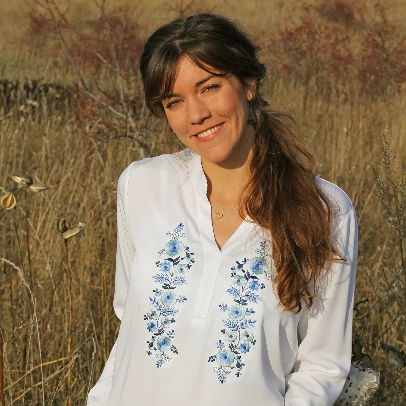 Blouse blanche pour femme, coupe ample, vêtement fluide, avec broderie Palóc bleue en colonnes florales délicates. Vue du buste.