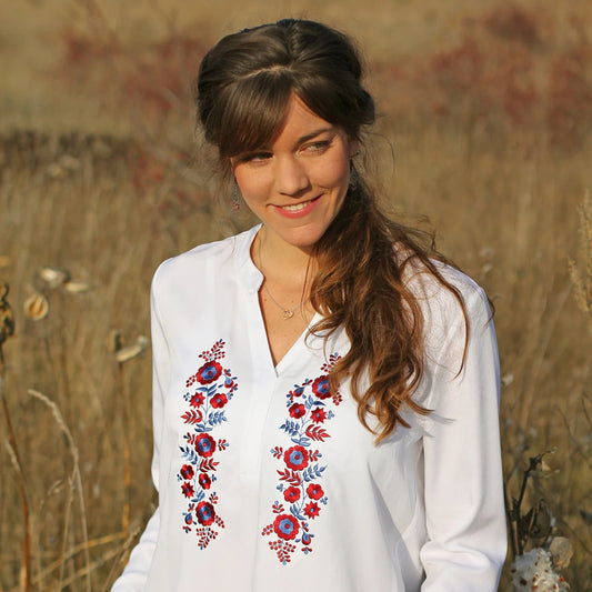 Blouse blanche pour femme, à manches longues, col en V et avec broderies Palóc rouges et bleues sur le devant. Coupe ample. Vue du buste.
