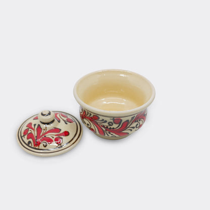 Petite boîte ronde en céramique de Corund avec couvercle décoré à la main. Motifs floraux rouges traditionnels.