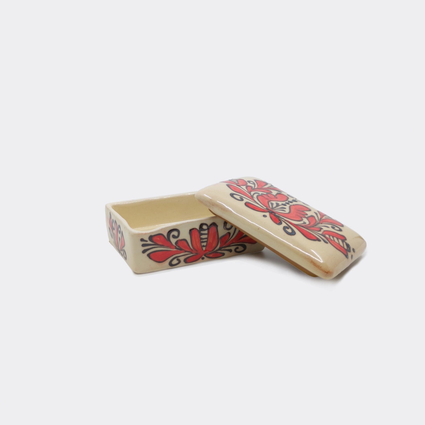 Petite boîte décorative en céramique de Corund ouverte avec son  couvercle. Décor floral rouge aux contours brun-noir sur fond crème émaillé.