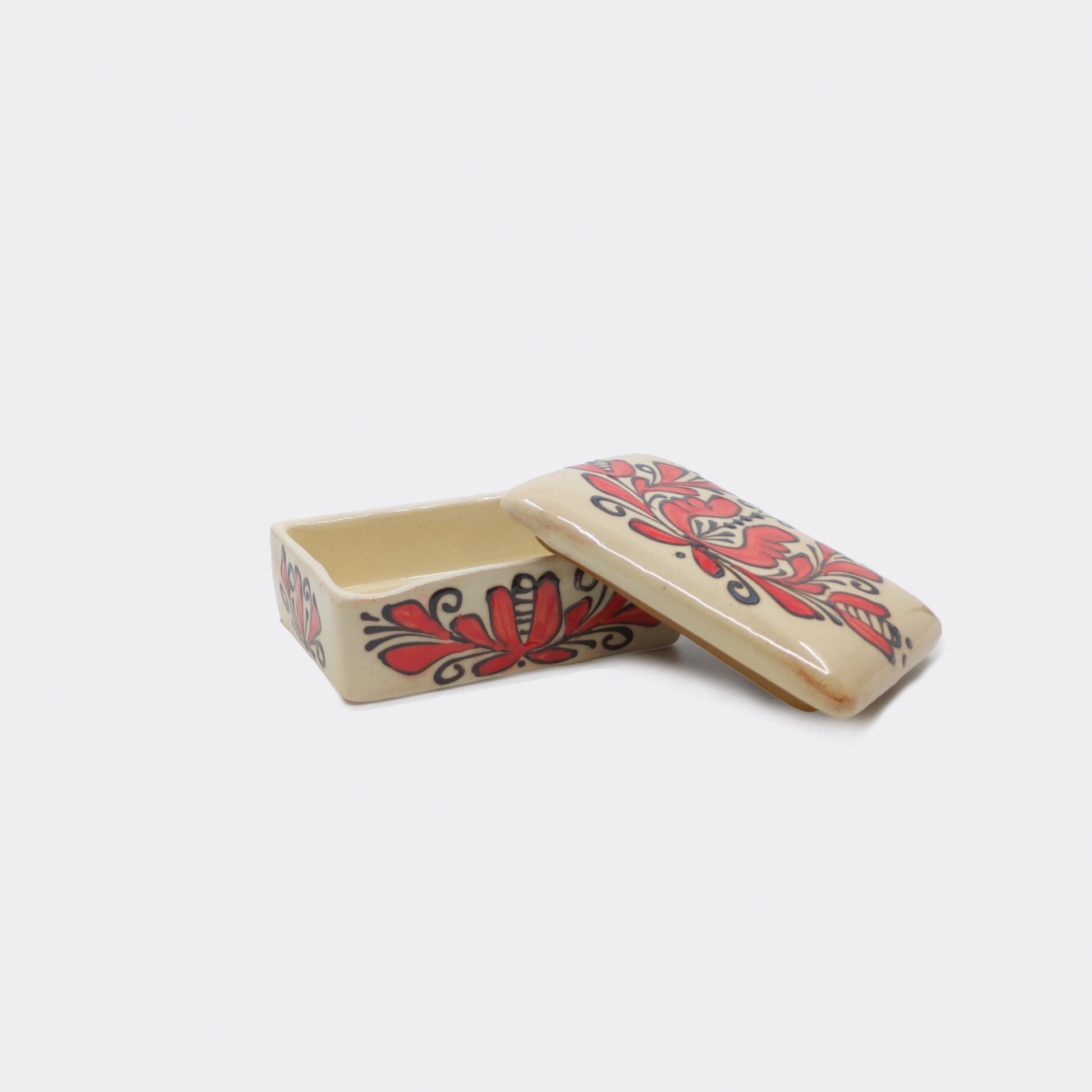 Petite boîte décorative en céramique de Corund ouverte avec son  couvercle. Décor floral rouge aux contours brun-noir sur fond crème émaillé.