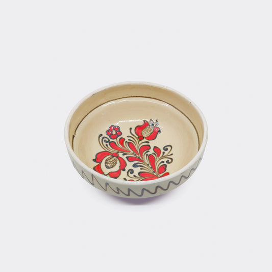 Bol en céramique artisanale de Corund vu du dessus. Motif floral rouge intérieur et glaçure crème.