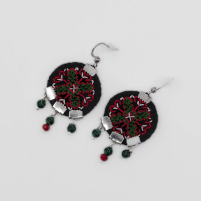 Boucles d’oreilles brodées à la main sur feutre noir, motif géométrique inspiré du folklore serbe, perles pendantes. Vue de face.