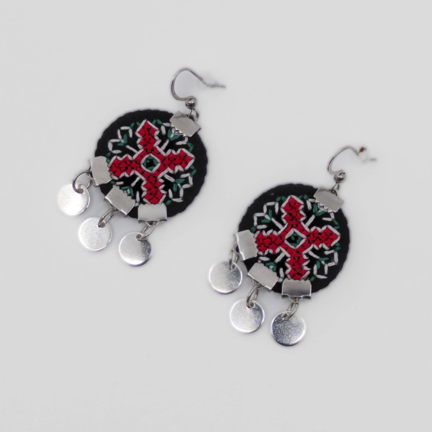 Boucles d’oreilles textiles brodées rouge et noir, motif traditionnel balkanique avec petits éléments métalliques pendants.