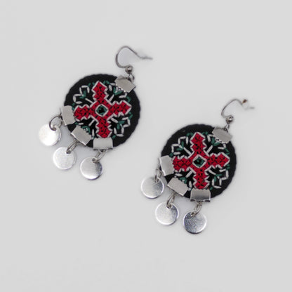 Boucles d’oreilles textiles brodées rouge et noir, motif traditionnel balkanique avec petits éléments métalliques pendants.