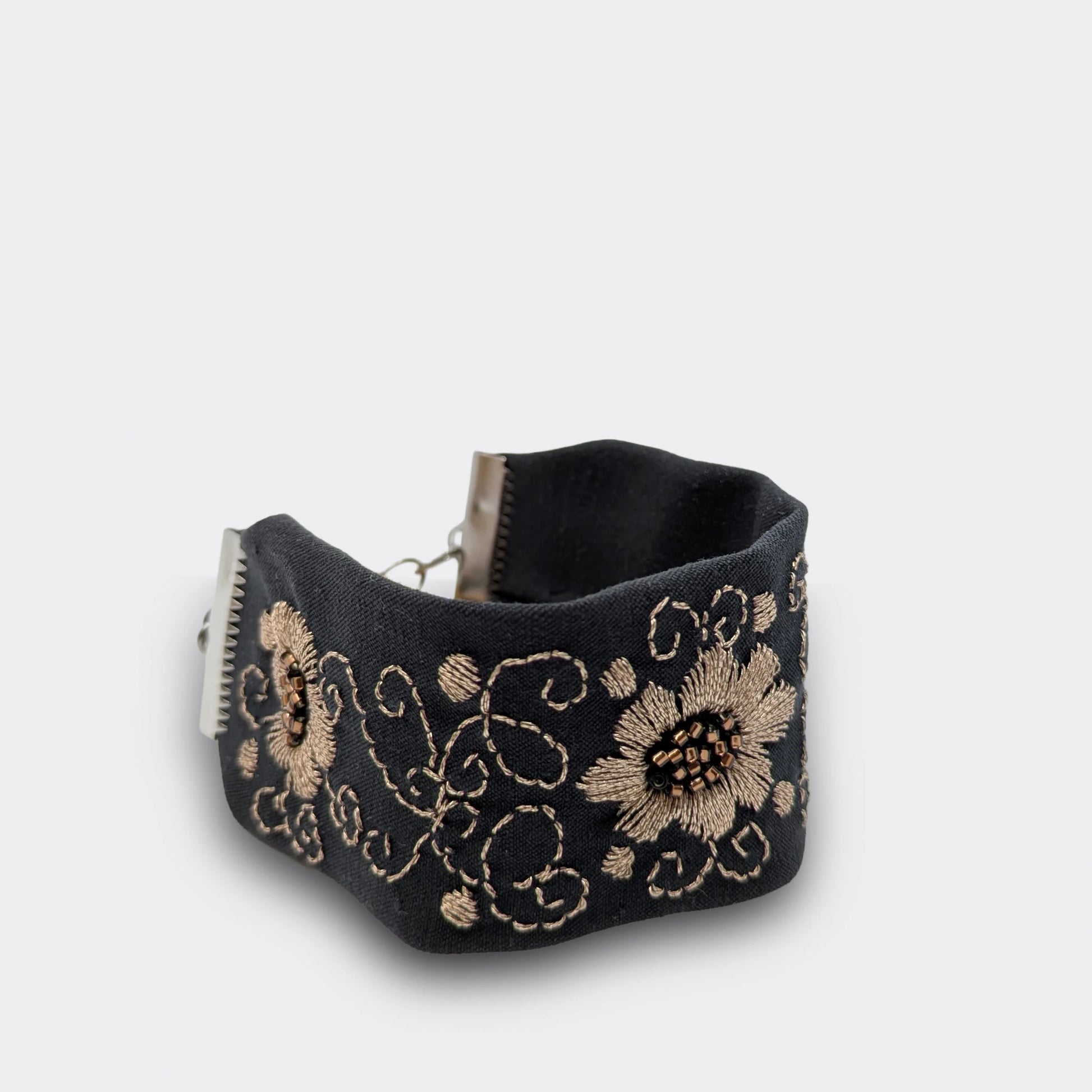 Motif floral champagne brodé main sur brocart noir, décor lumineux inspiré du folklore régional. Bracelet artisanal fabriqué en Serbie, vue de près
