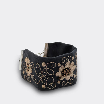 Motif floral champagne brodé main sur brocart noir, décor lumineux inspiré du folklore régional. Bracelet artisanal fabriqué en Serbie, vue de près