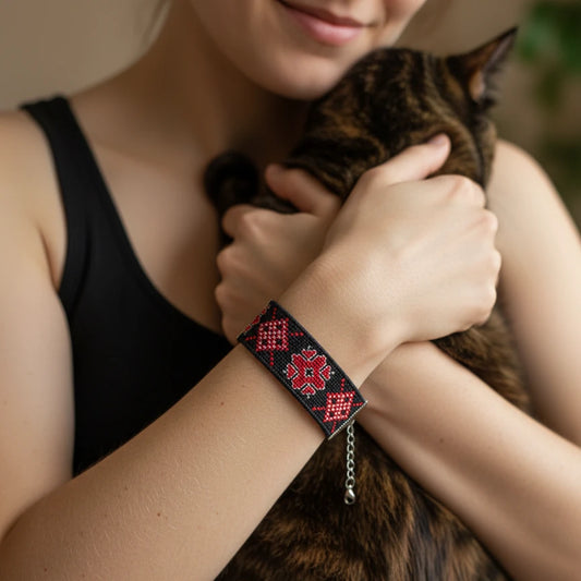 Bracelet artisanal rouge brodé sur fond noir en toile Panama. Motifs géométriques traditionnels serbes au fil rouge et blanc.