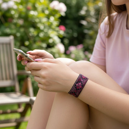 Bracelet artisanal en toile Panama noire brodé au point croisé. Les motifs géométriques en rose grenat rappellent les motifs traditionnels serbes.