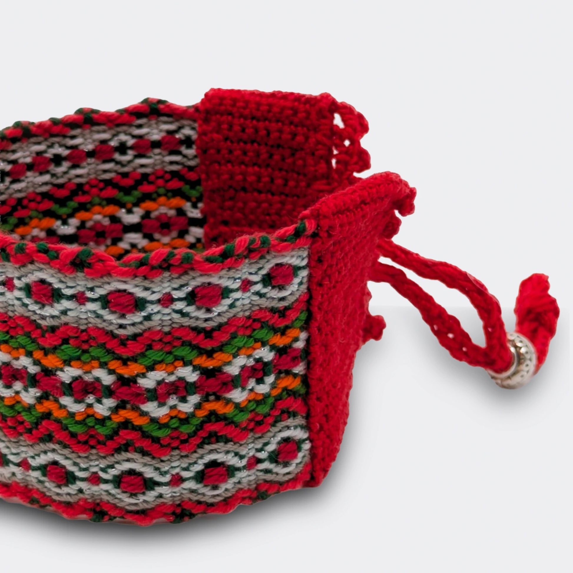 Détail de la texture tissée et crochetée d'un bracelet d'inspiration ethnique, entrelacs de fils colorés et bordure festive. Vue de détail.