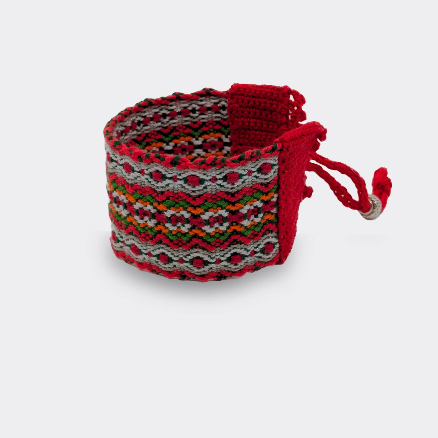 Manchette artisanale tissée et bordée de crochet appliqué, association de fils rouges, verts et blancs. Vue de face.