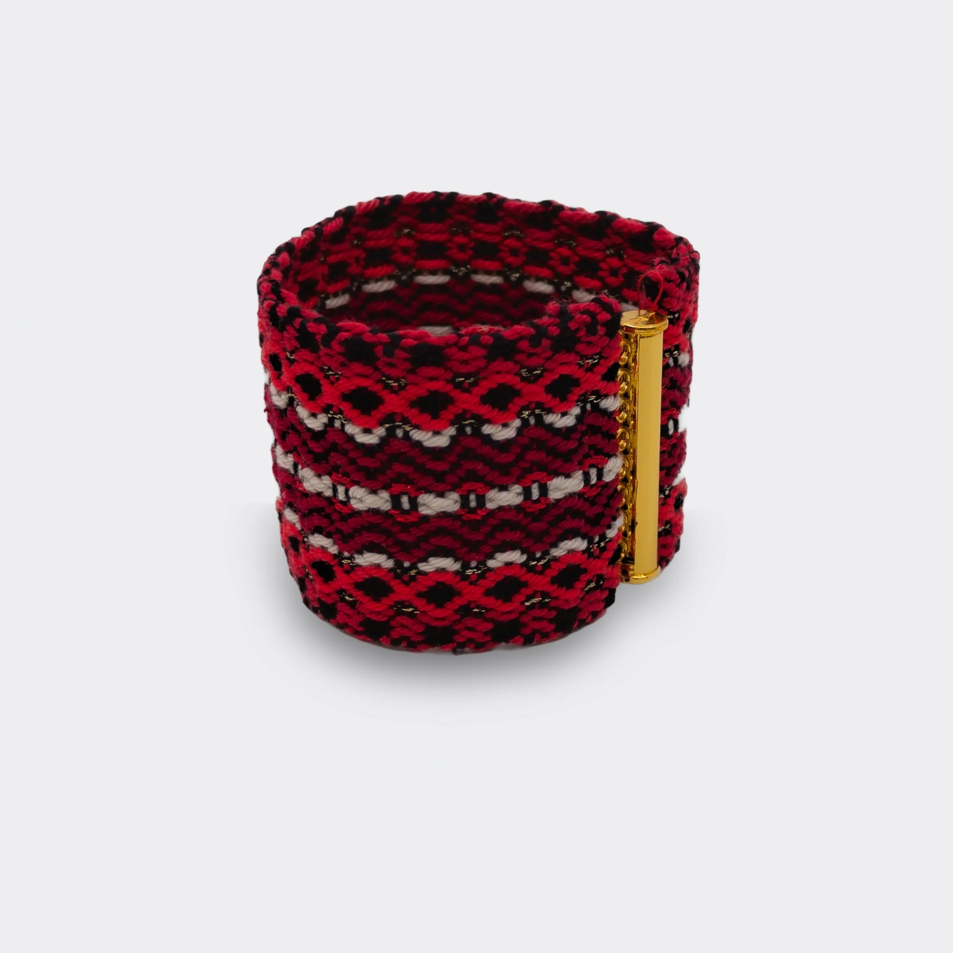 Bracelet tissé en fils rouges, noirs et blancs, motifs géométriques typiques du tissage balkanique, vue de face.