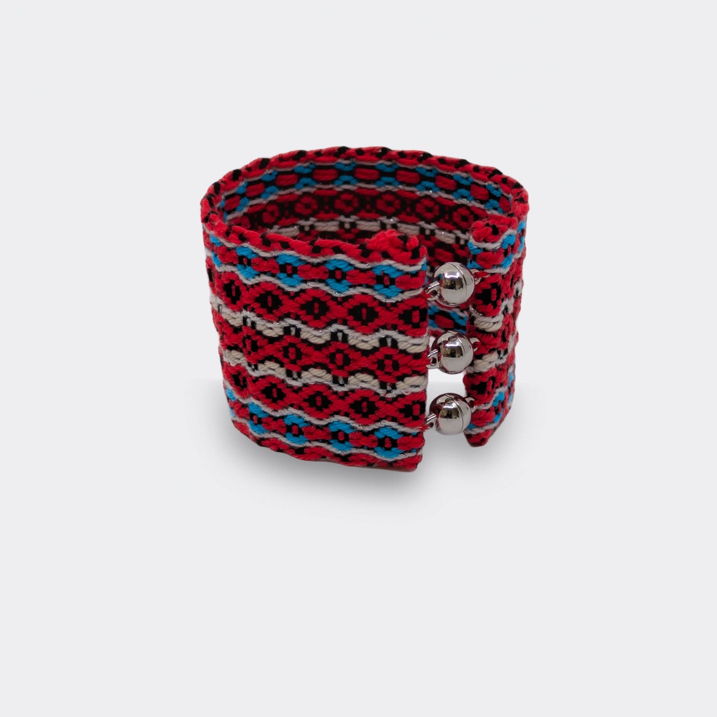 Bracelet tissé rouge et bleu en fil de coton, motifs géométriques inspirés du folklore balkanique, vue de face.