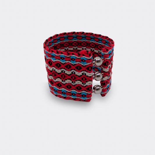 Bracelet tissé rouge et bleu en fil de coton, motifs géométriques inspirés du folklore balkanique, vue de face.