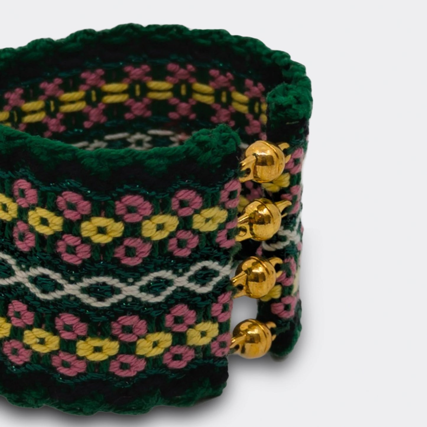 Gros plan sur la trame textile aux motifs floraux d'un bracelet tissé en fil de coton. Fermoir à bille.