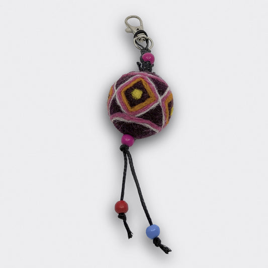 Breloque Bogdan constituée d'une boule en feutre rouge foncé et jaune entièrement faite à la main