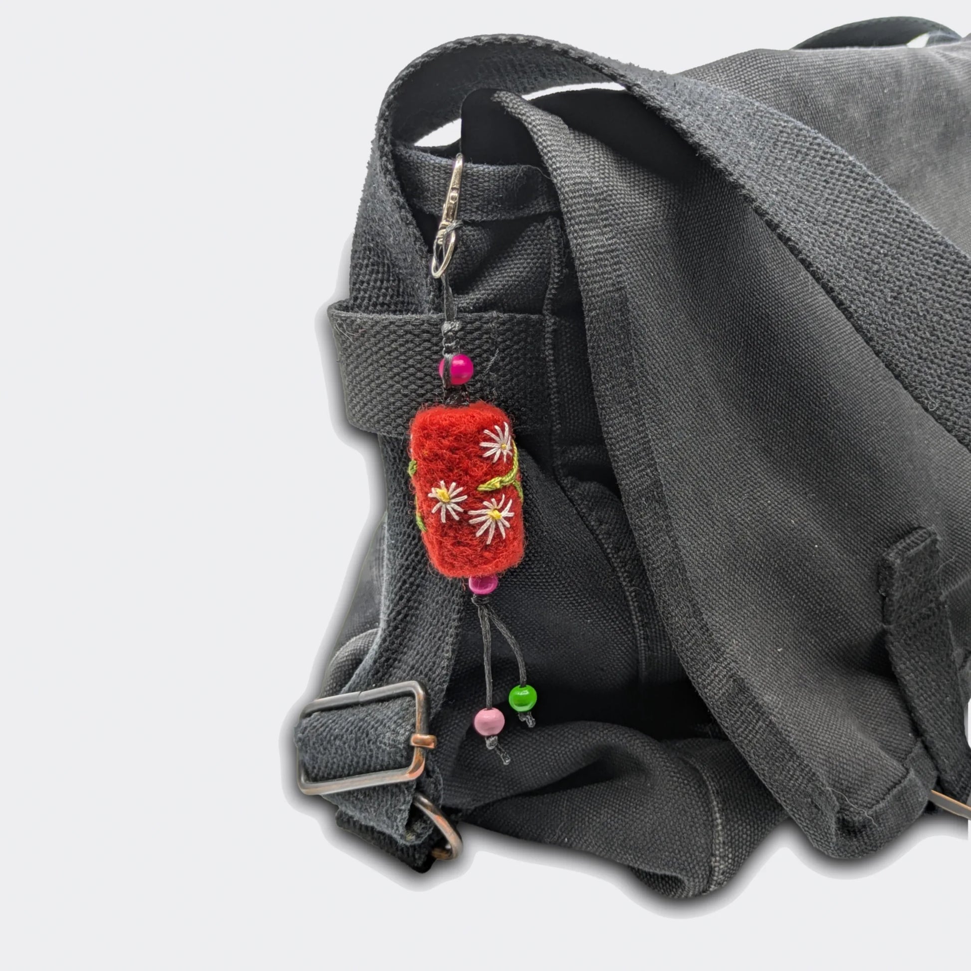 Accessoire de sac Tania, petit cylindre rouge, accroché sur un sac