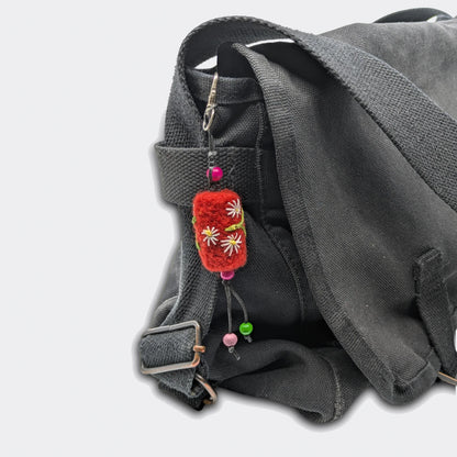 Accessoire de sac Tania, petit cylindre rouge, accroché sur un sac