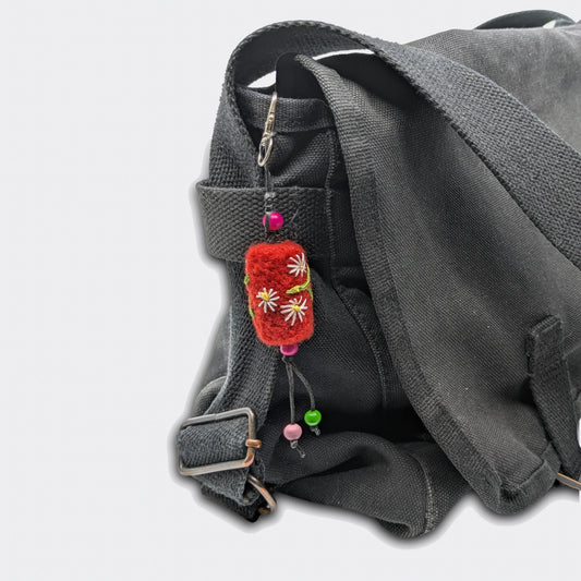 Accessoire de sac Tania, petit cylindre rouge, accroché sur un sac