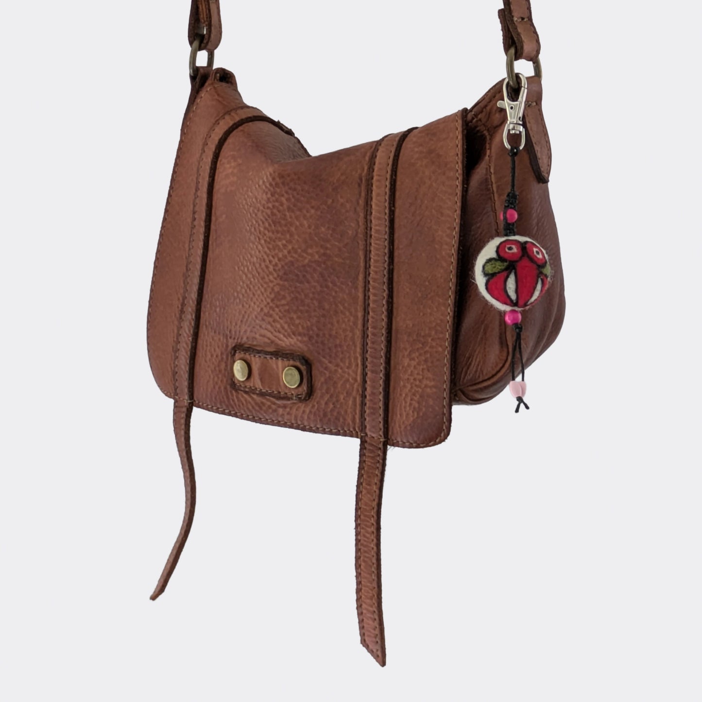 Breloque de sac en laine feutrée faite main accrochée à un sac en cuir