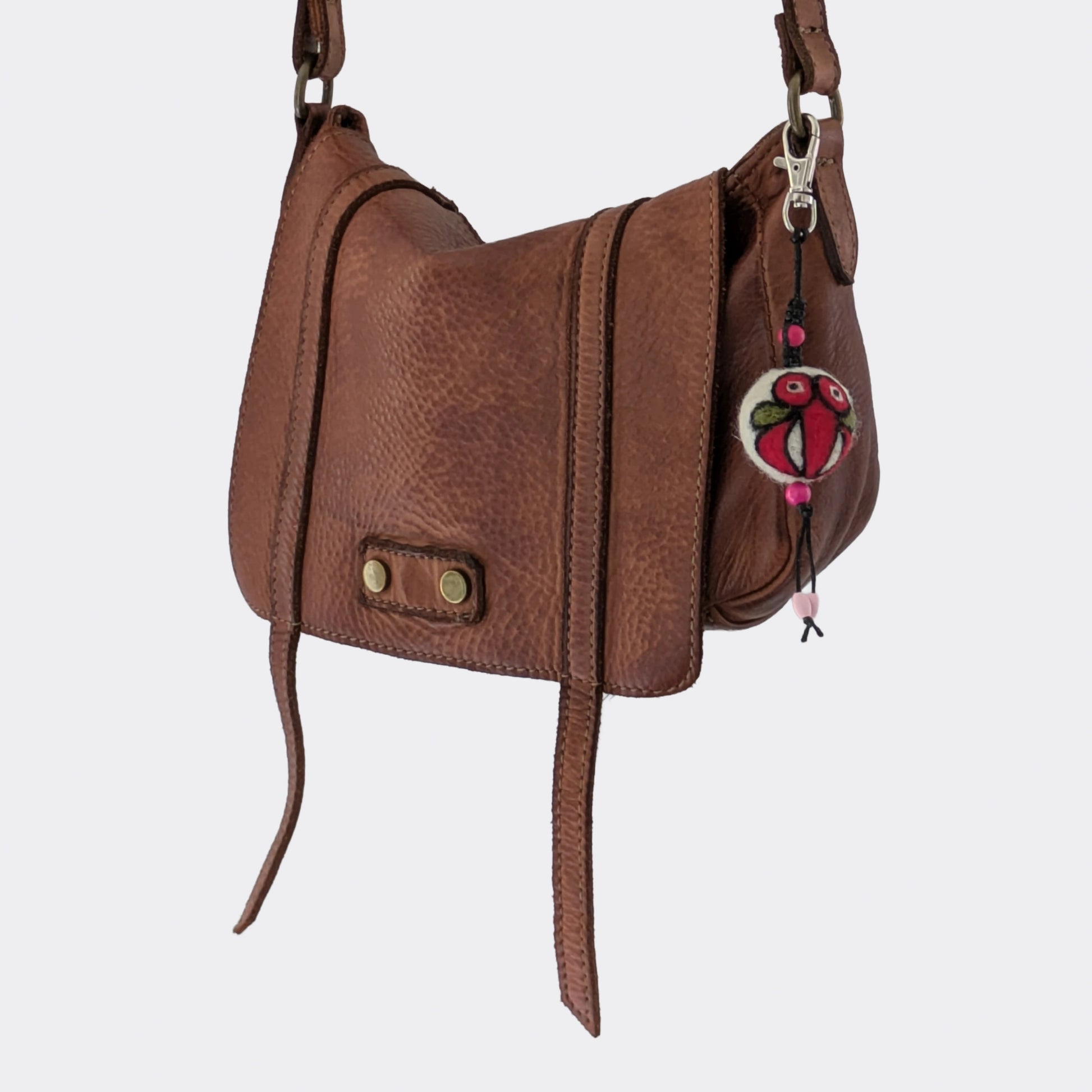 Breloque de sac en laine feutrée faite main accrochée à un sac en cuir
