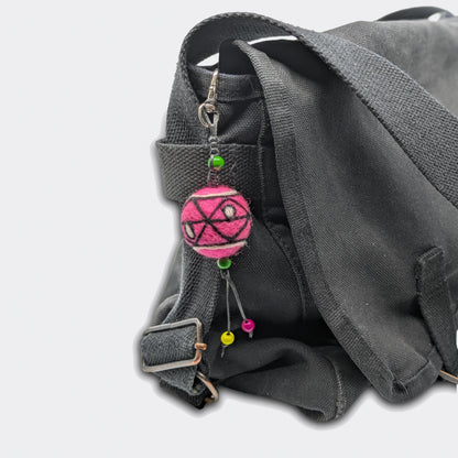 Breloque de sac Slavka avec une boule en feutre rose  attachée sur un sac