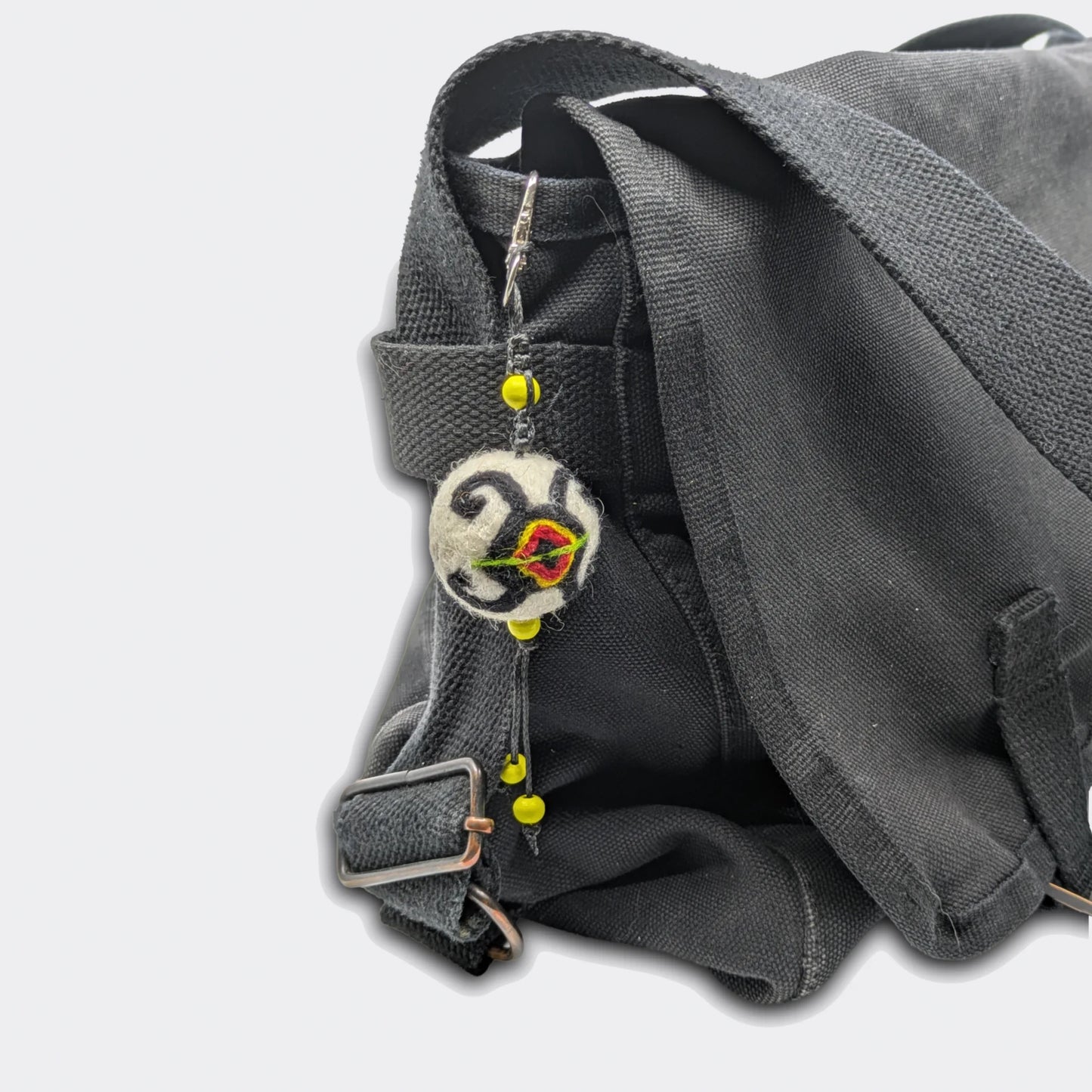 Vue de la breloque Stanislav en feutre, décor tortue traditionnelle rouge et noir. Elle est accrochée sur un sac