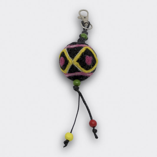 Breloque de sac Voïvod en feutre, coloré en noir avec motifs jaunes et roses.